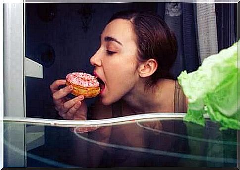 A woman eating a donut at night.