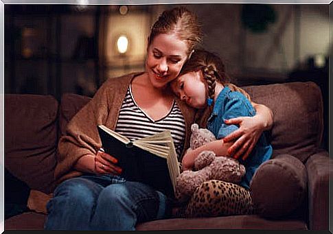A mother on the couch reading with her daughter